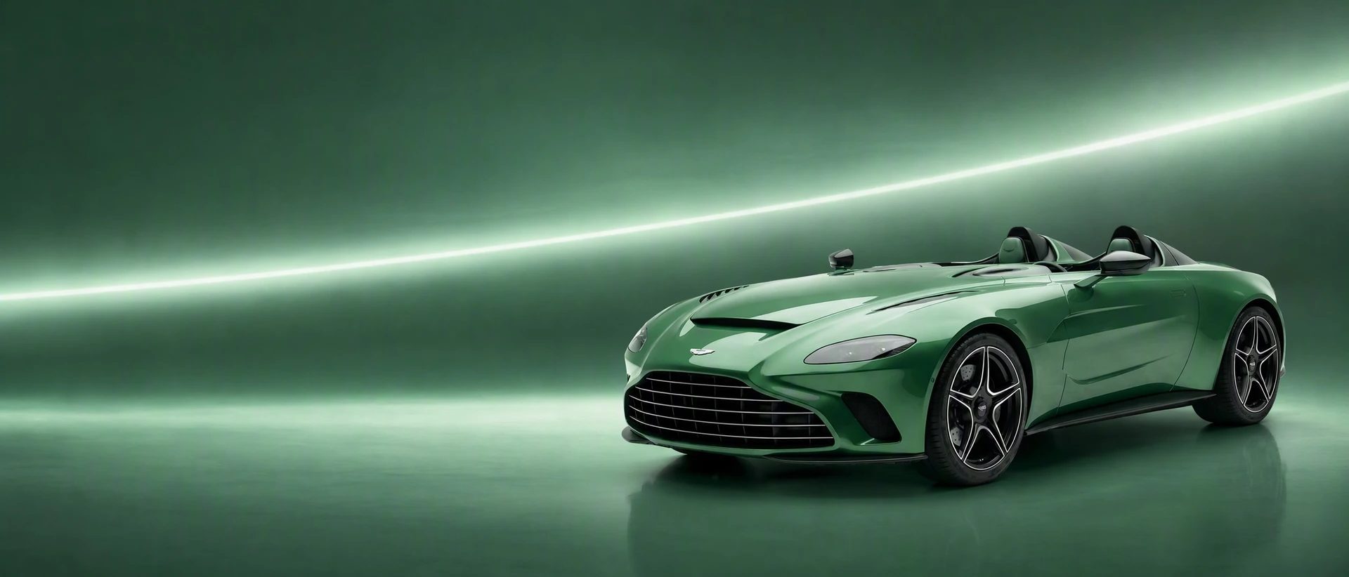 A green Aston Martin V12 Speedster, front three-quarter view on a racing-green field with a silver arc