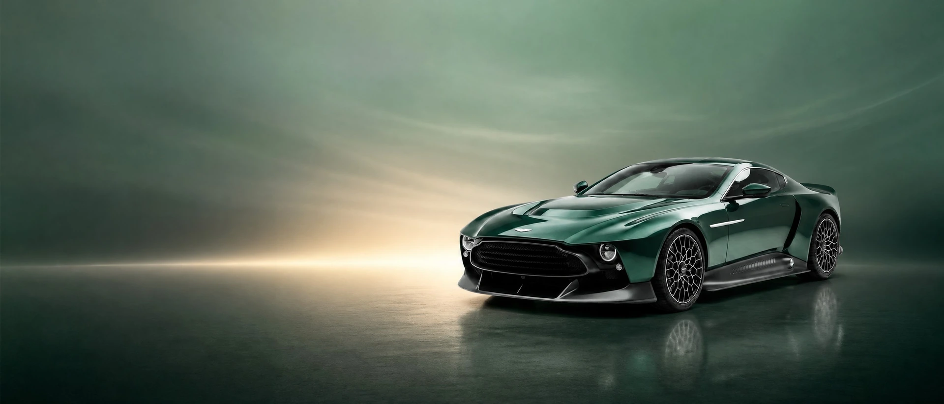 A dark green Aston Martin Valour, front three-quarter view on a forest-green field with a warm horizon