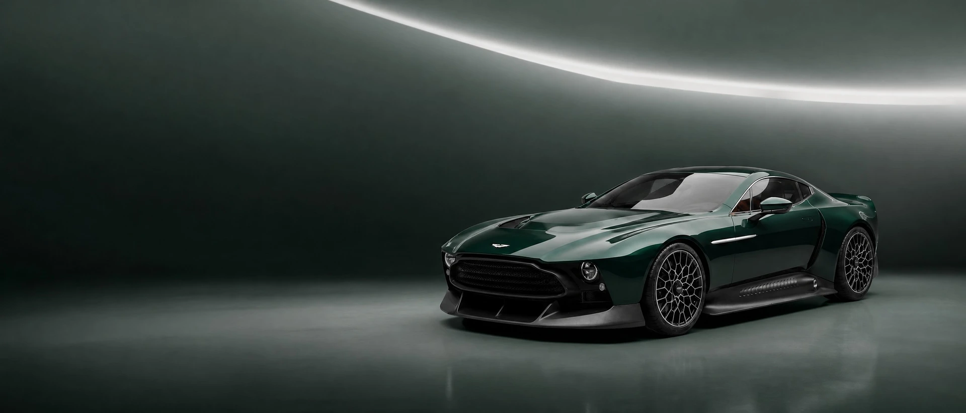 A dark green Aston Martin Victor, front three-quarter view on a graphite-green field with a silver sweep