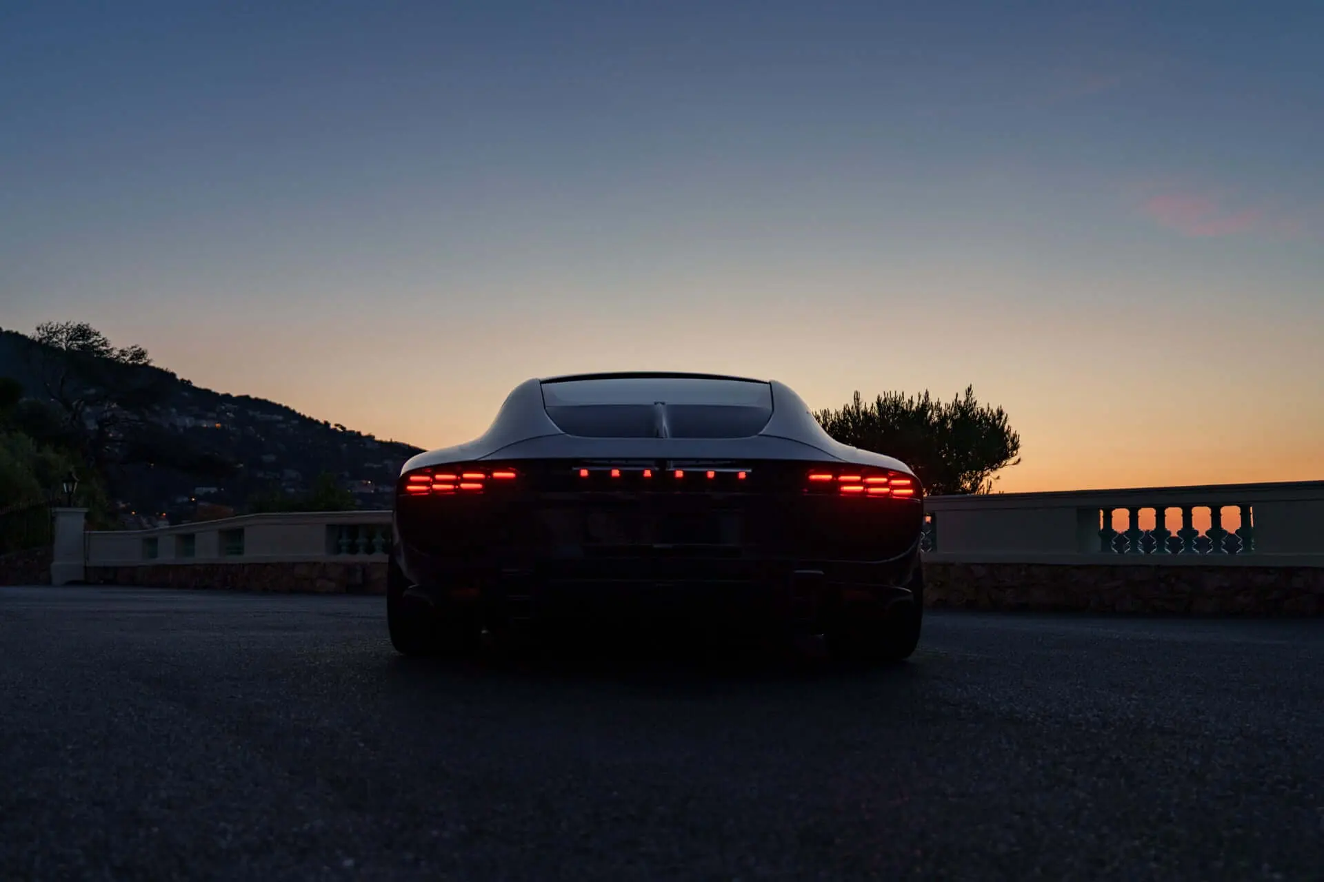 Brabus Bodo from behind at dusk above Monaco, taillight band lit against the evening sky