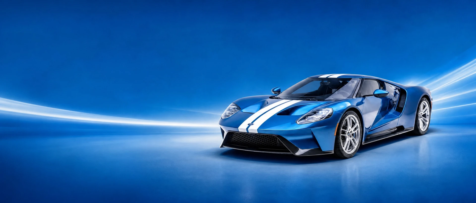 A metallic blue Ford GT with white centre stripes, front three-quarter view on a blue field with racing light streaks