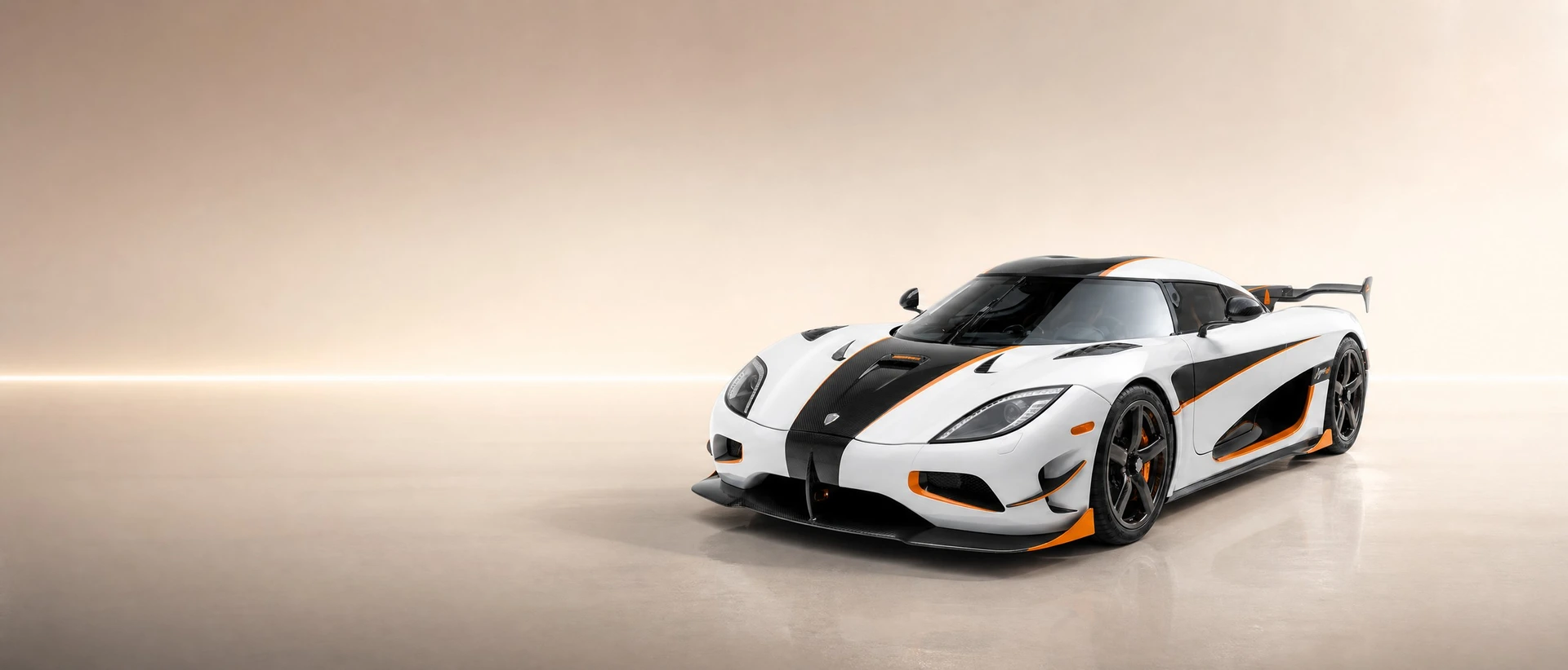 A white Koenigsegg Agera RS with exposed carbon and orange accents, front three-quarter view on a champagne field with one straight line of light