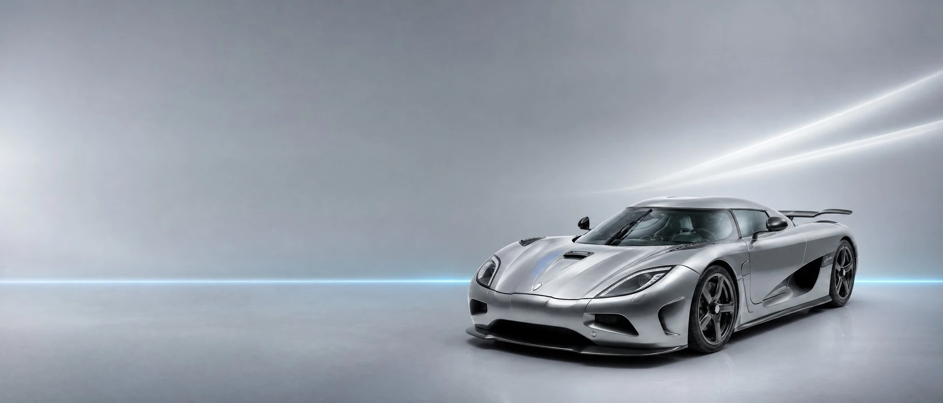 A silver Koenigsegg Agera, front three-quarter view on a silver field with a cyan needle of light