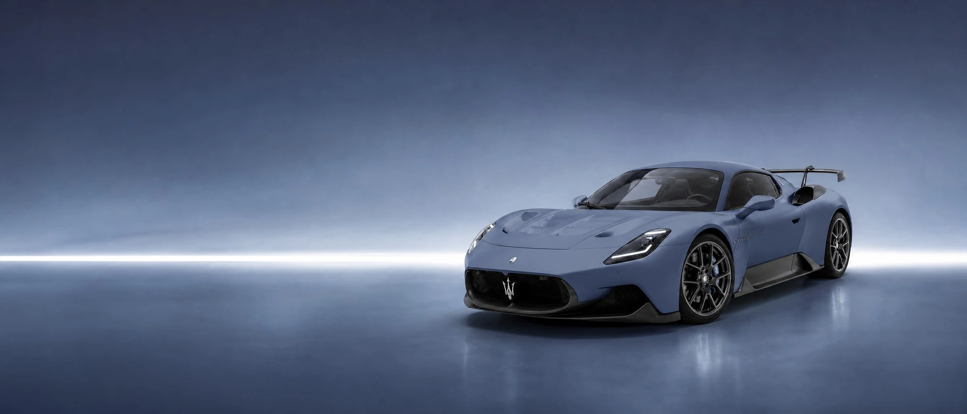 A blue-grey Maserati GT2 Stradale, front three-quarter view on a slate-blue field with a crisp line of light