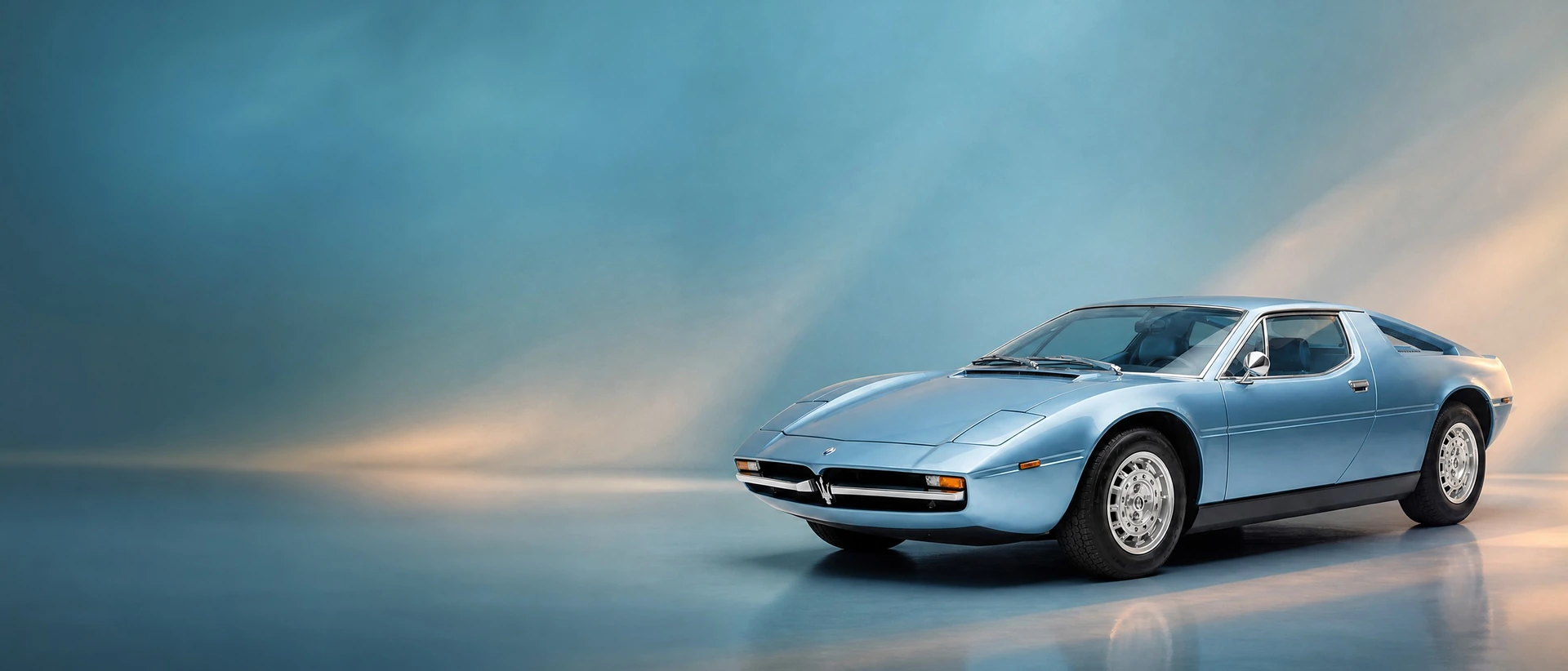 A Maserati Merak, front three-quarter view on a teal field with lamplight haze