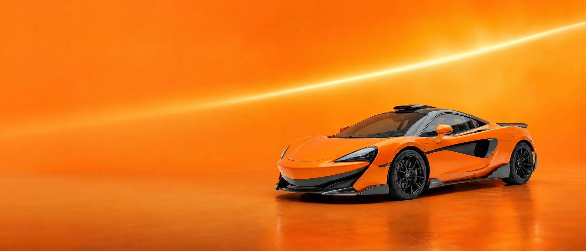 An orange McLaren 600LT, front three-quarter view on a papaya field with a streak of light