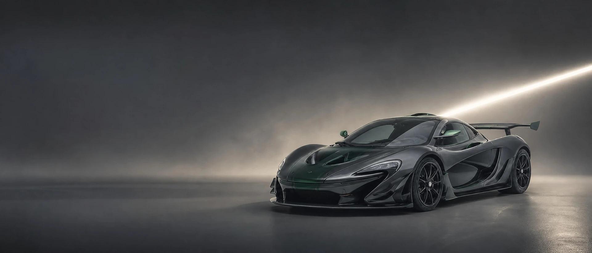 A dark green-grey McLaren P1 GTR, front three-quarter view on a graphite field with a yellow-white seam