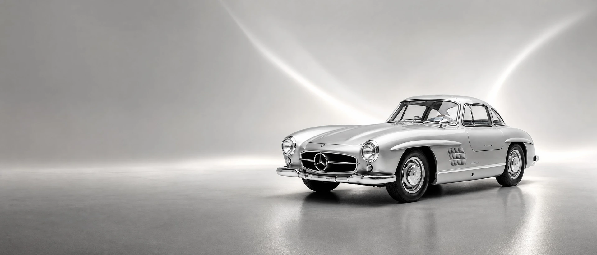 A silver Mercedes-Benz 300 SL Gullwing coupé, front three-quarter view on a silver field with wings of light