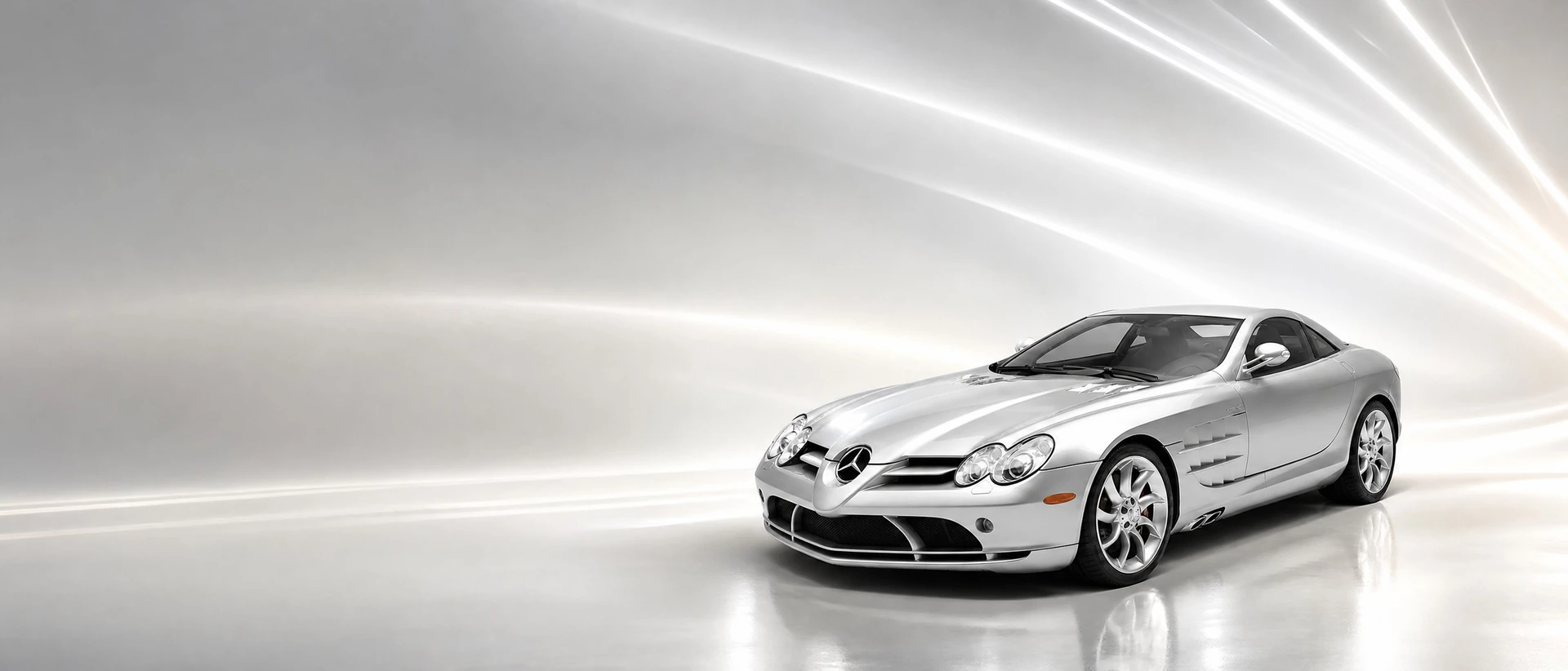 A silver Mercedes-Benz SLR McLaren, front three-quarter view on a silver field with sweeping light trails