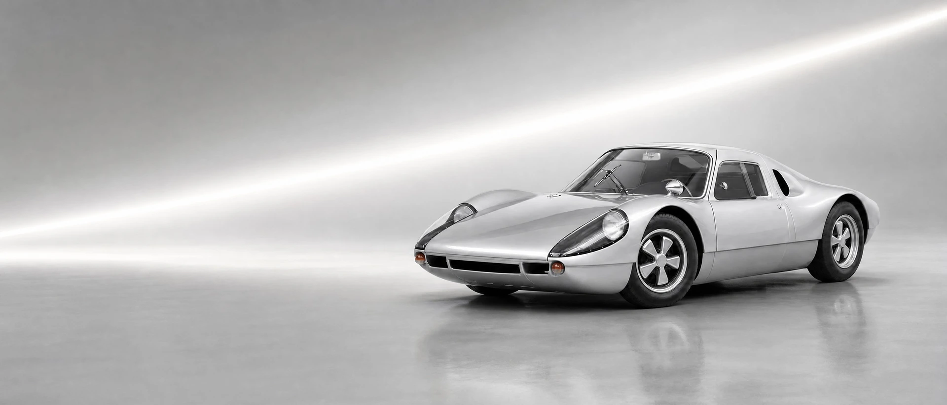 A silver Porsche 904 Carrera GTS, front three-quarter view on a white-grey field with a racing streak