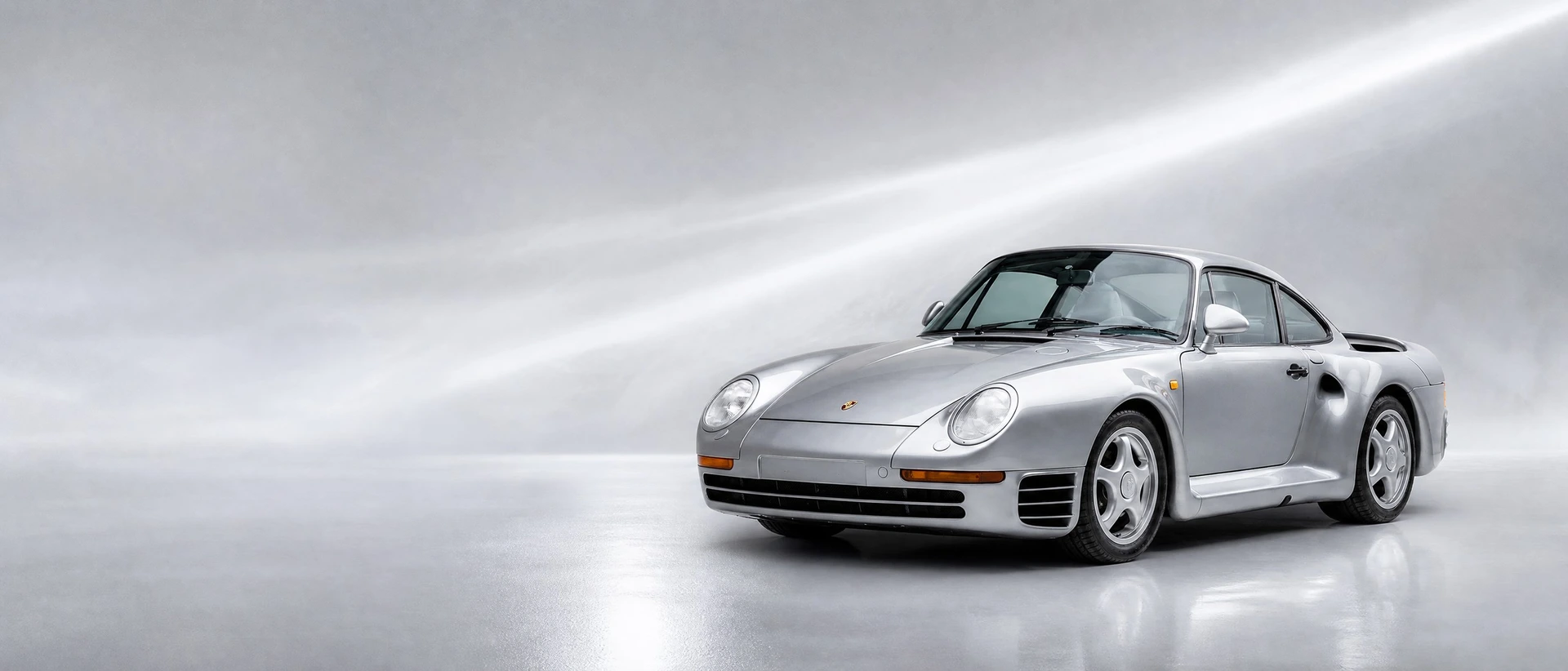 A silver Porsche 959, front three-quarter view on a silver field with a cool sweep of light