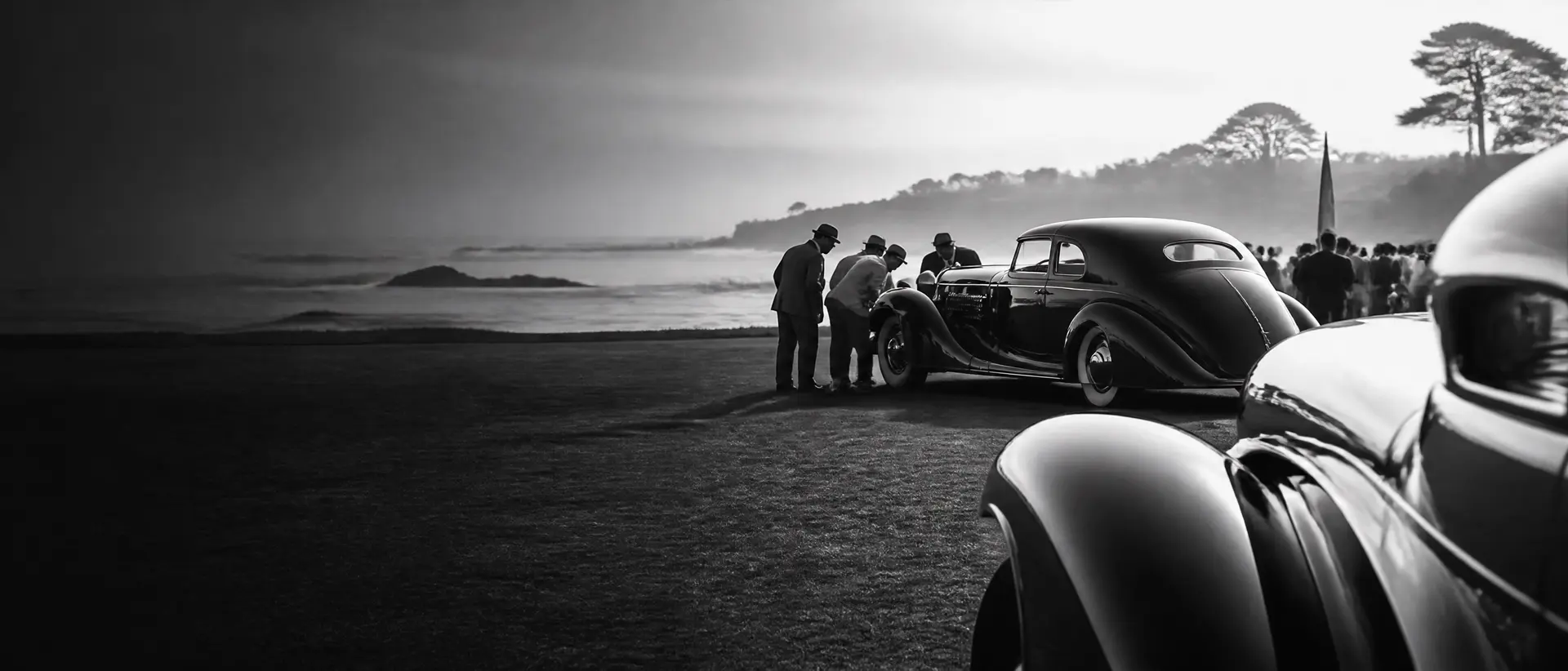 Black-and-white morning scene on a coastal golf course, a 1930s coachbuilt masterpiece on the fairway, Pacific surf behind, judges’ silhouettes leaning in, a fender line cropped at the frame edge