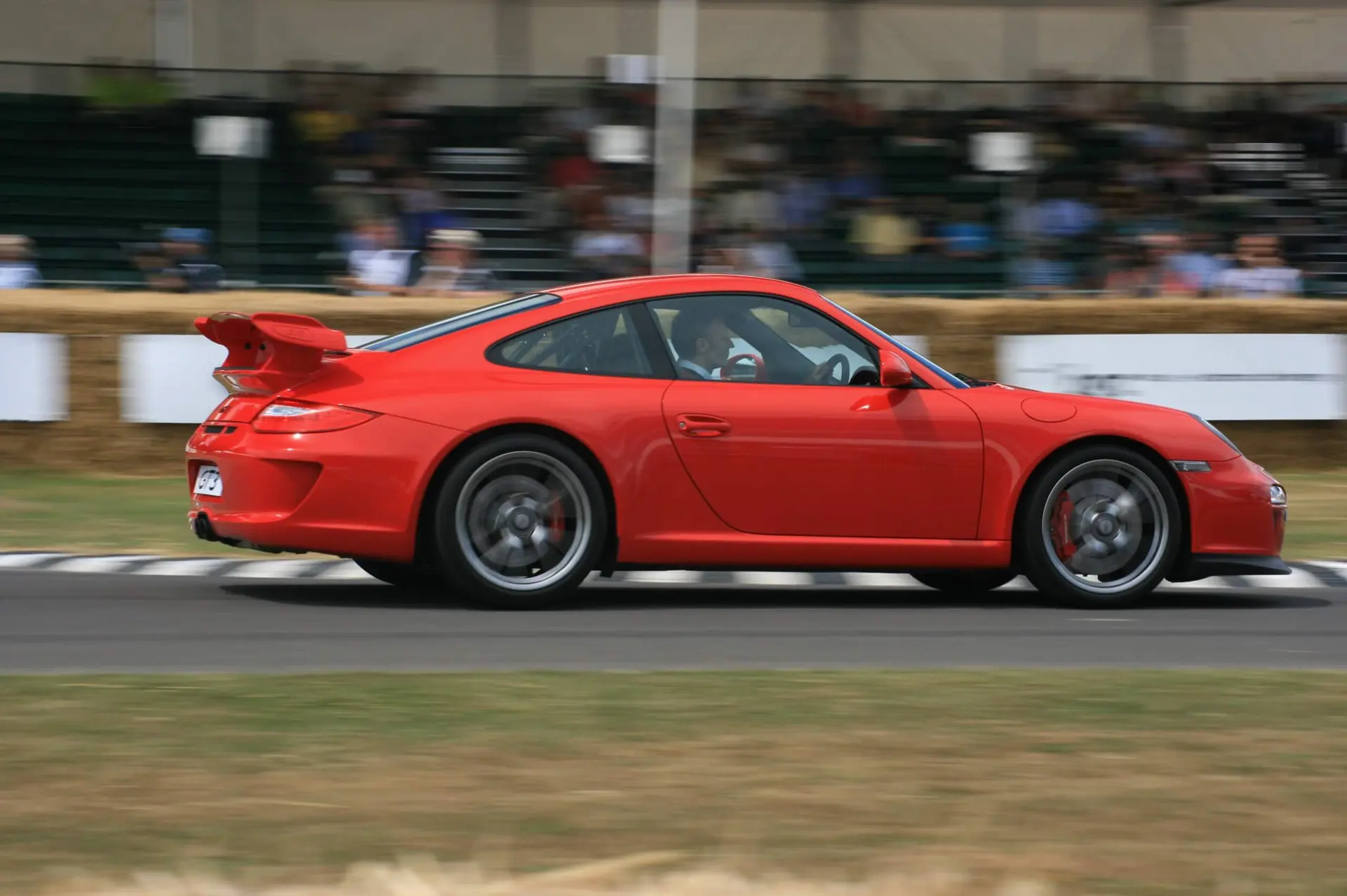 Andreas Preuninger driving a red Porsche 911 GT3 3.8 up the hill at the Goodwood Festival of Speed