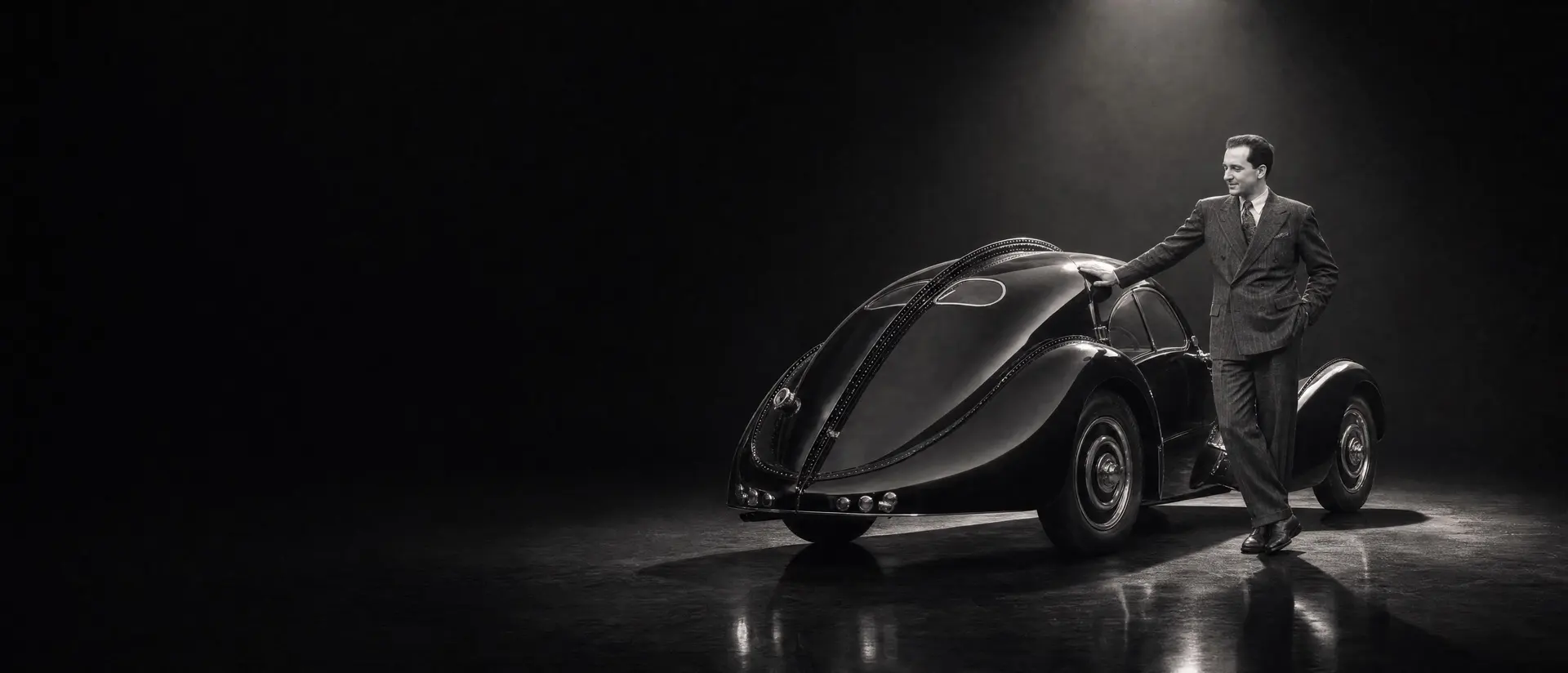 Jean Bugatti in a 1930s suit, one hand resting on the riveted dorsal seam of a Bugatti Type 57 SC Atlantic under a single spotlight