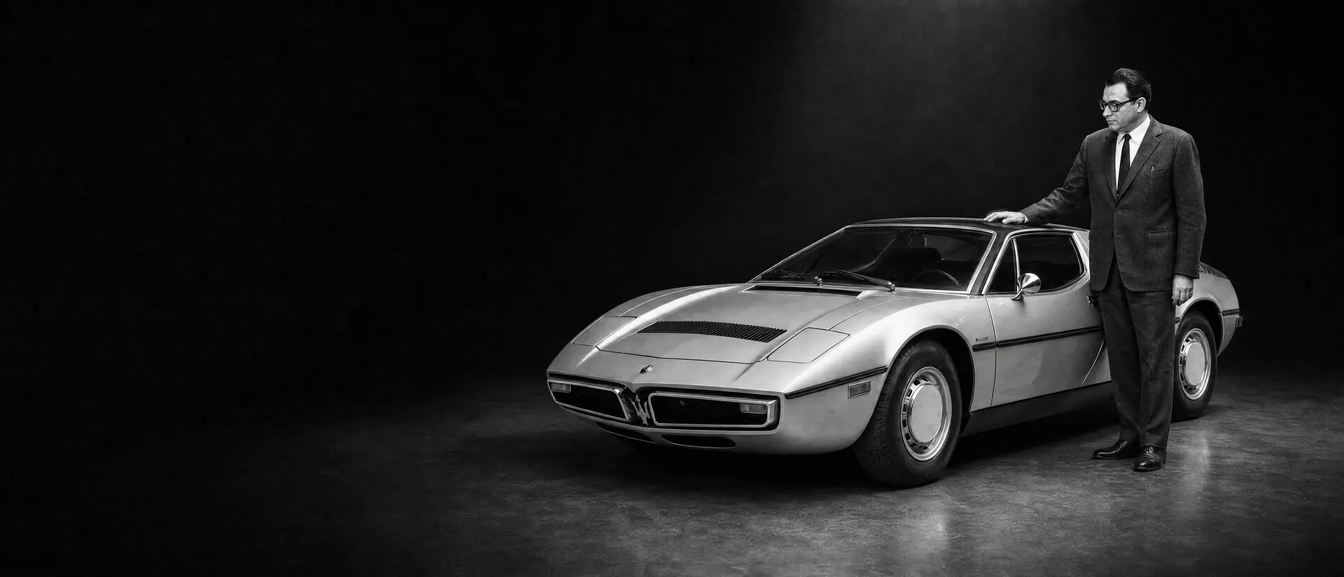 Paolo Stanzani beside a Lamborghini Countach with its engine cover raised, under a single spotlight