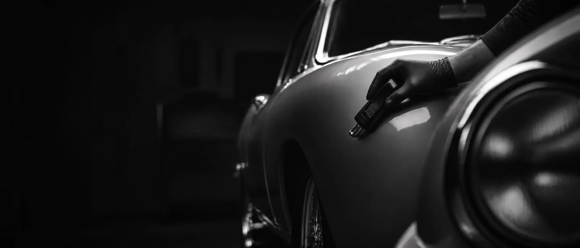 Raking light across bodywork under inspection, a cropped fender in the near foreground
